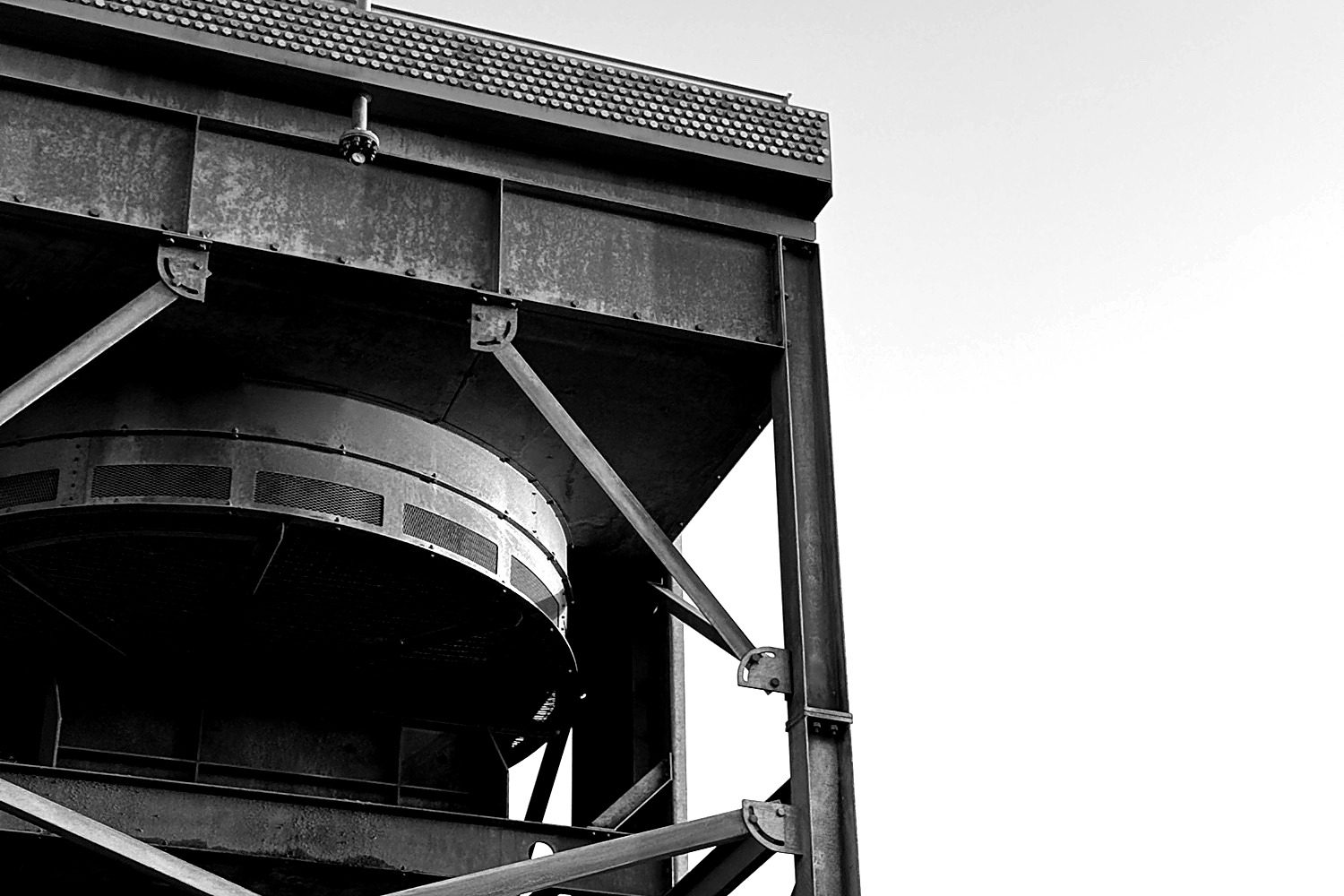 Steel structural framing on an active industrial construction site, viewed from below against an open sky